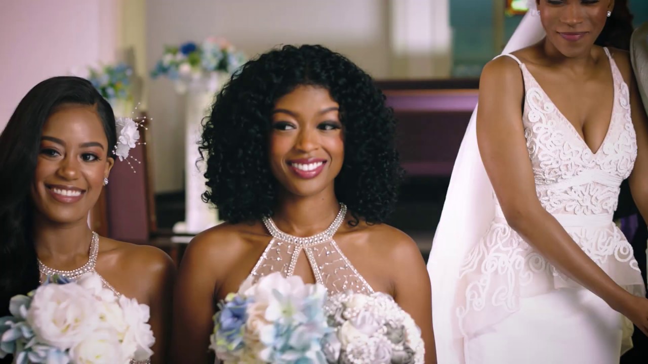 Bridal party in white gowns with bouquets before a floral backdrop, Always a Bridesmaid, production design by Myra Barrera