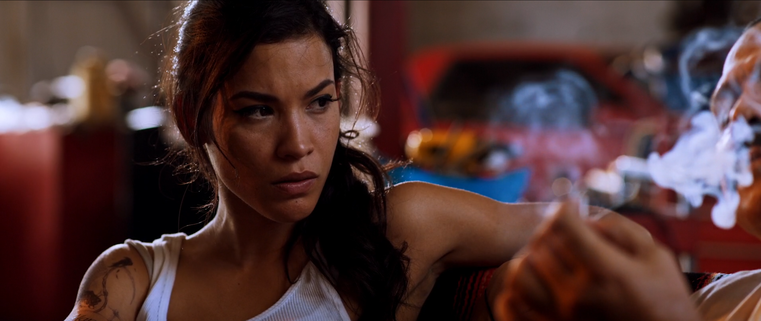 Tattooed character in a red-lit smoky interior in Avenge the Crows