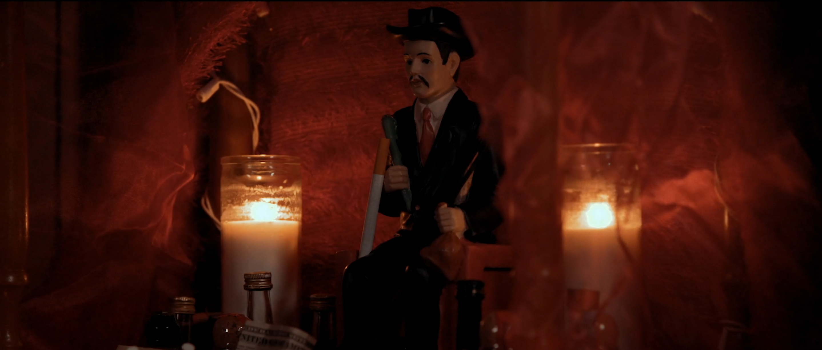 Red-lit interior with a figure behind two tall candles in Avenge the Crows