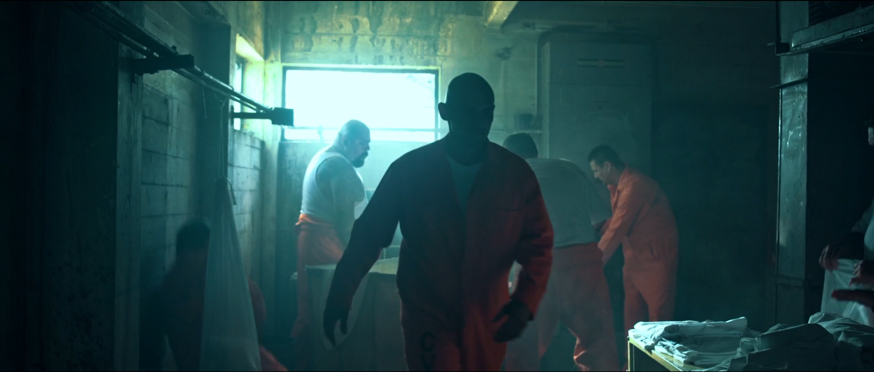 Dim corridor with inmates in orange jumpsuits and a bright doorway, Avenge the Crows