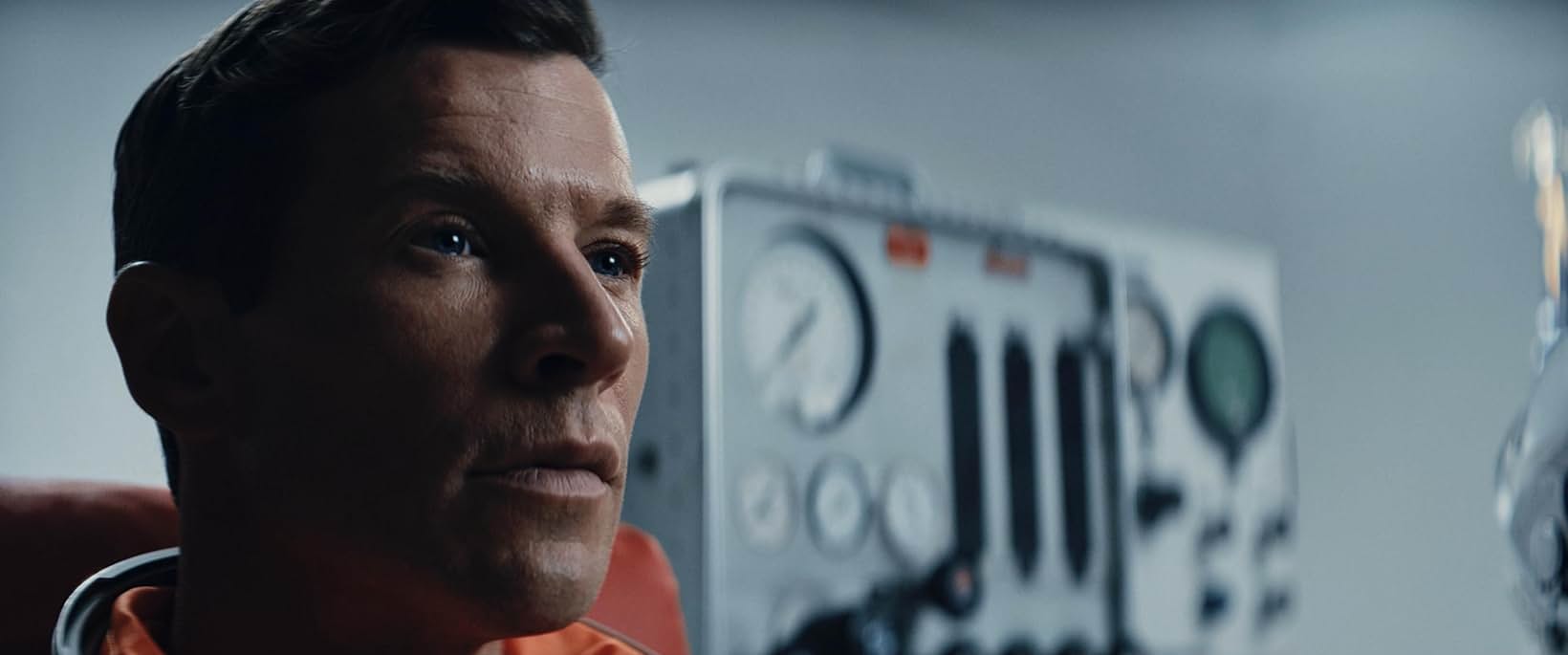 Test pilot in an orange flight suit before a mid-century instrument console, Edge of Space