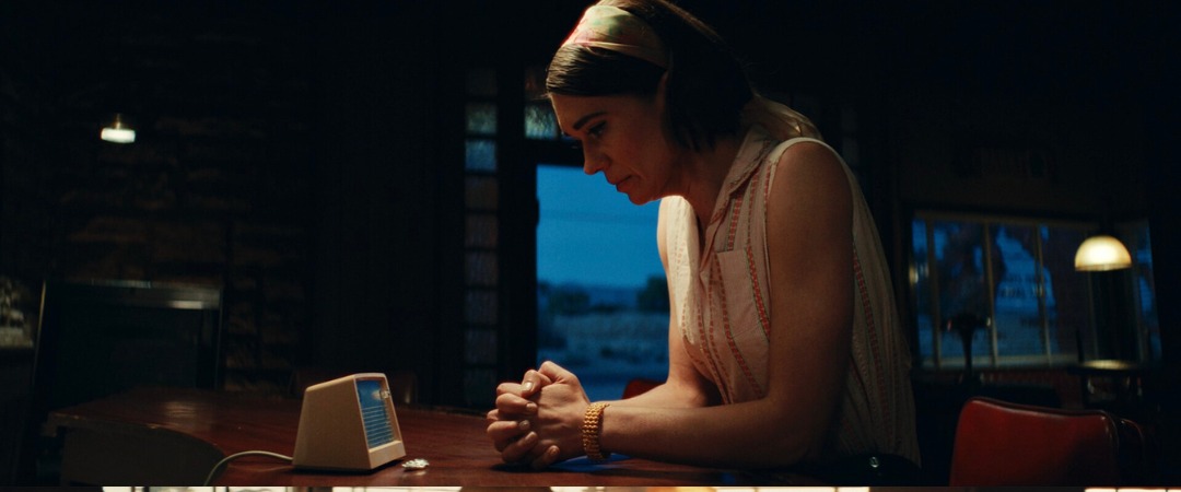 Character seated at a desk with a period radio beside a window, Edge of Space