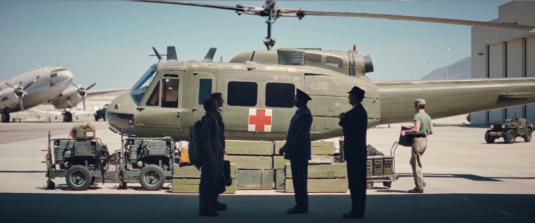 Airfield with a dressed and painted UH-1 medevac helicopter and uniformed crew, Edge of Space