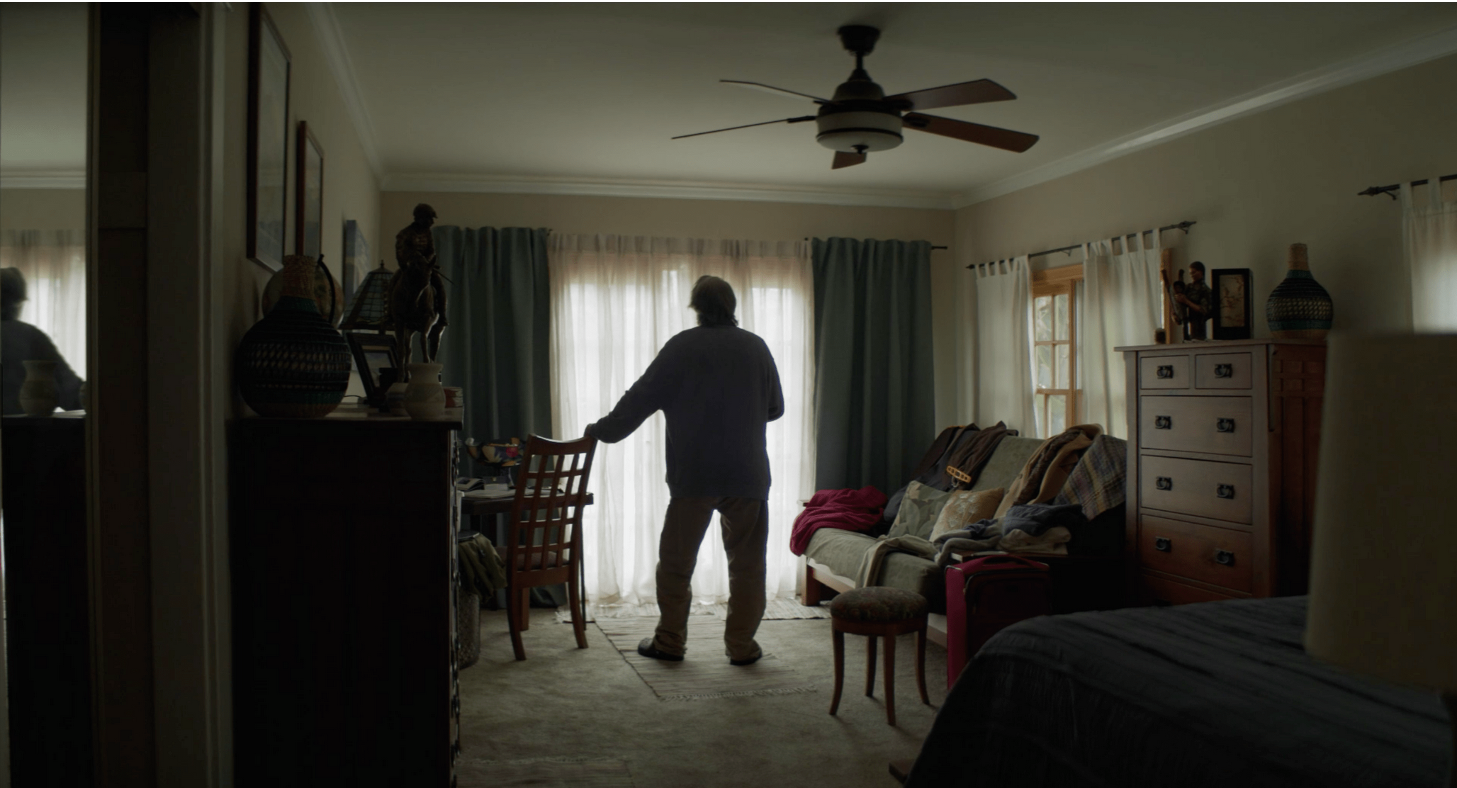 Character entering a furnished bedroom in The Liberator, production design by Myra Barrera
