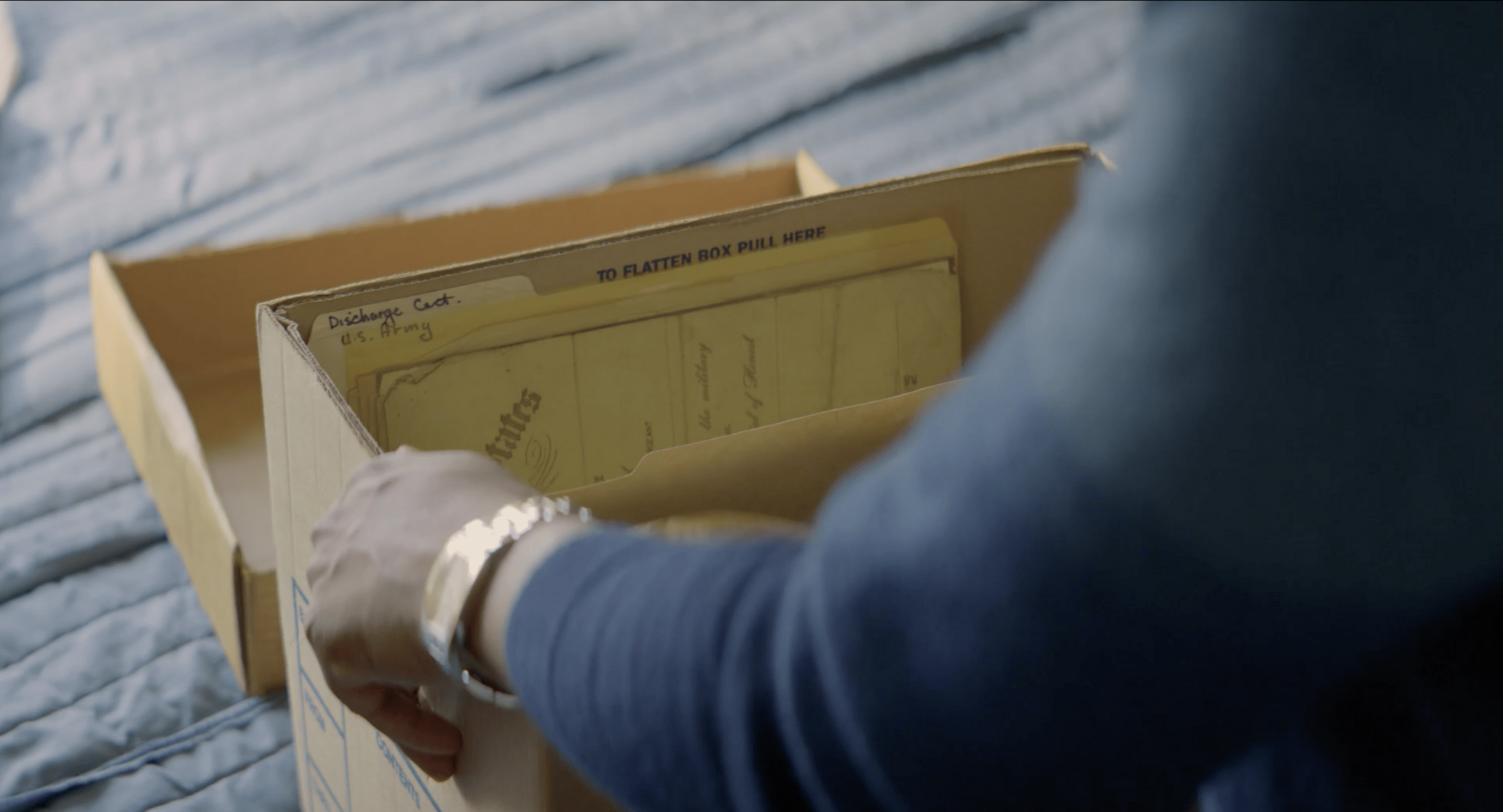 Hands lifting a document folder from a storage box, The Liberator