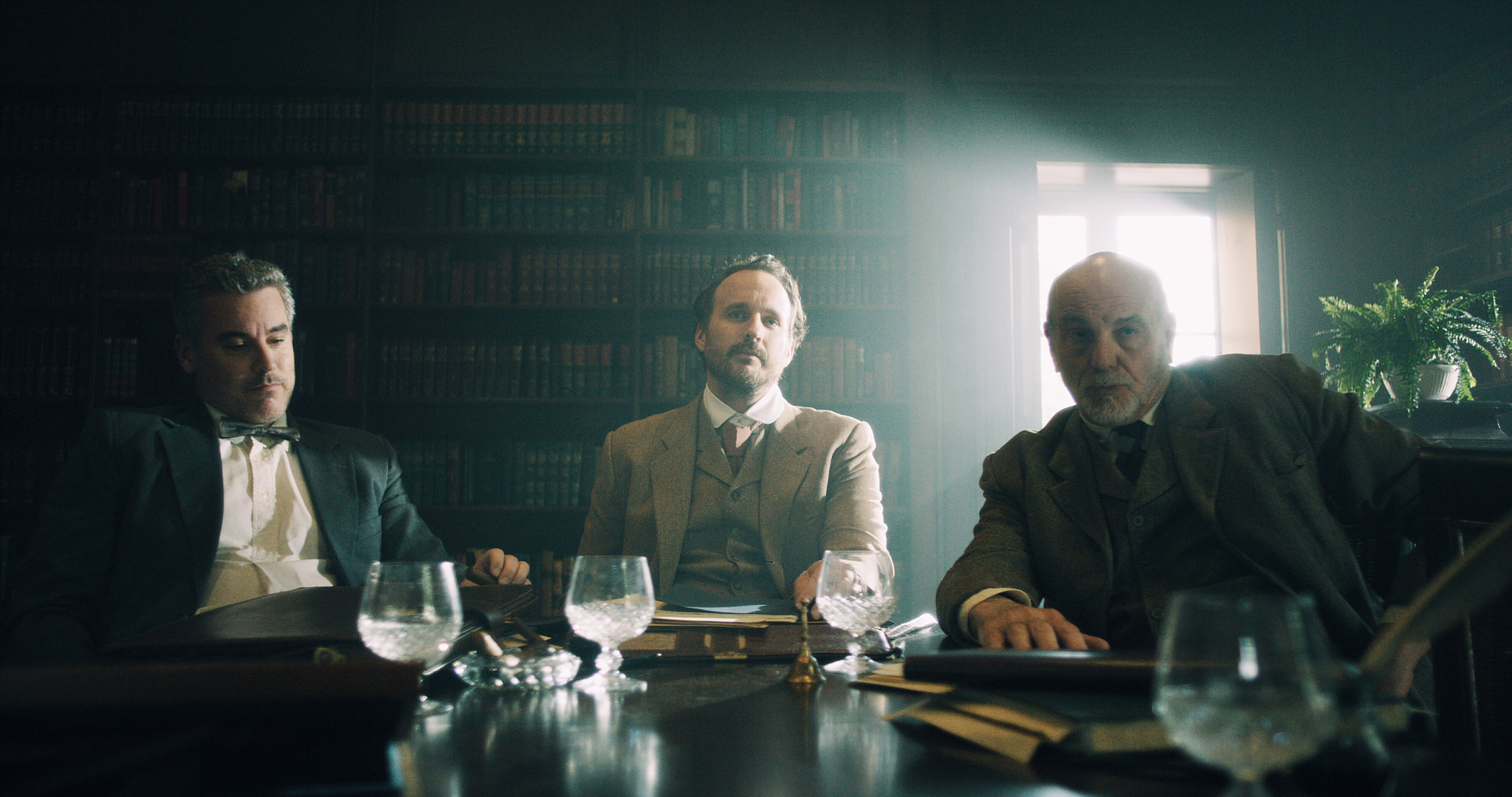 Period dining room from The Mad Whale, three men in Victorian dress at a candlelit table set with wine glasses