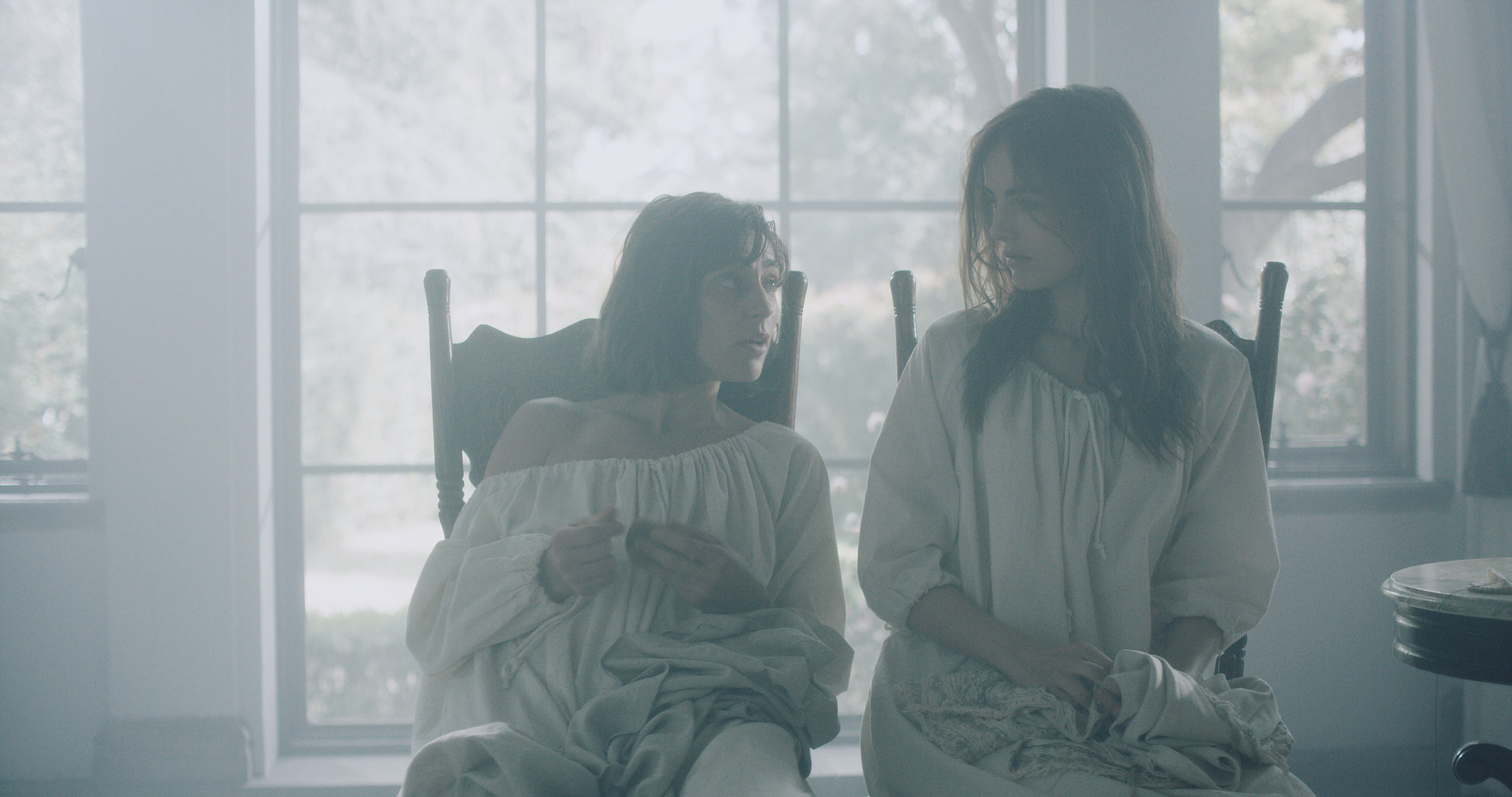 Two patients seated by tall windows in soft daylight, asylum interior from The Mad Whale