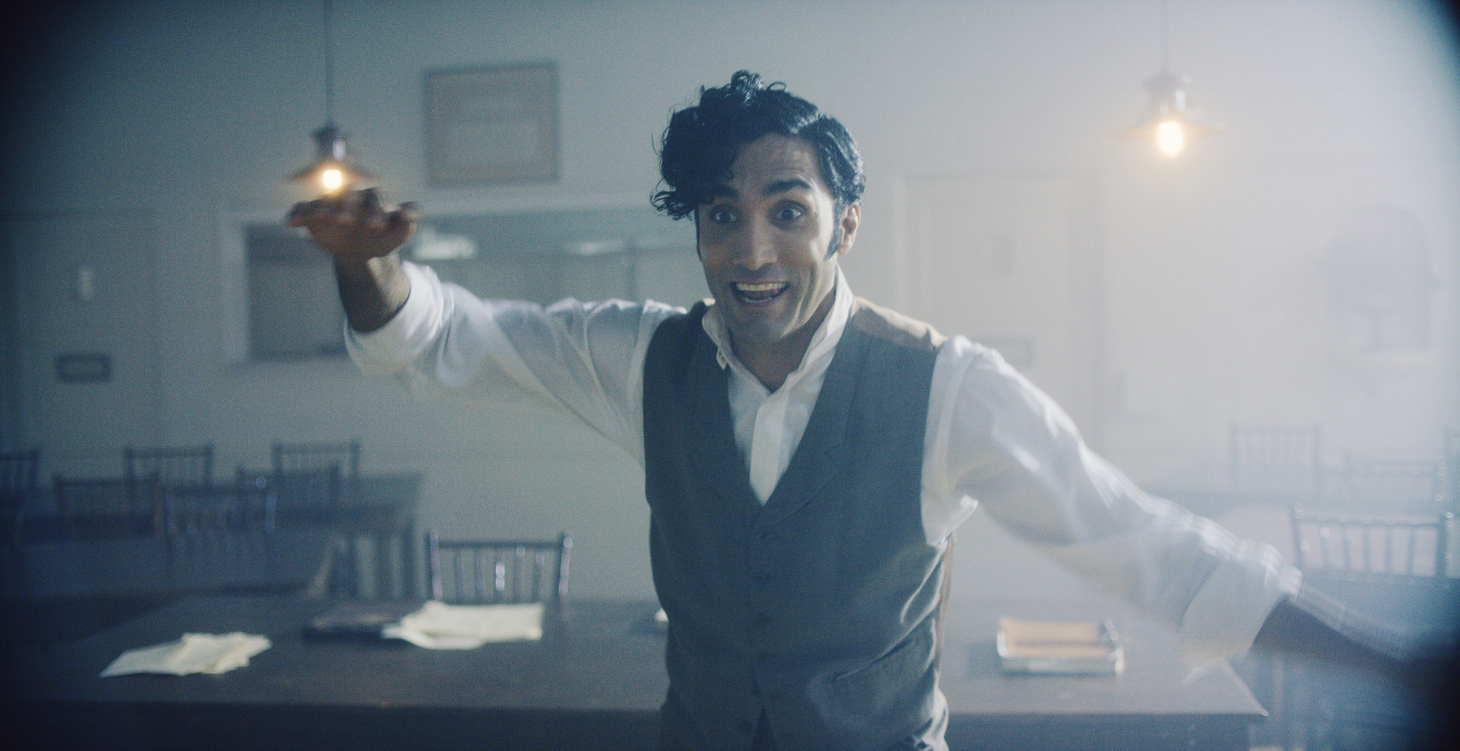 Young man in a waistcoat holding a glass up to the light in a bright asylum room, The Mad Whale