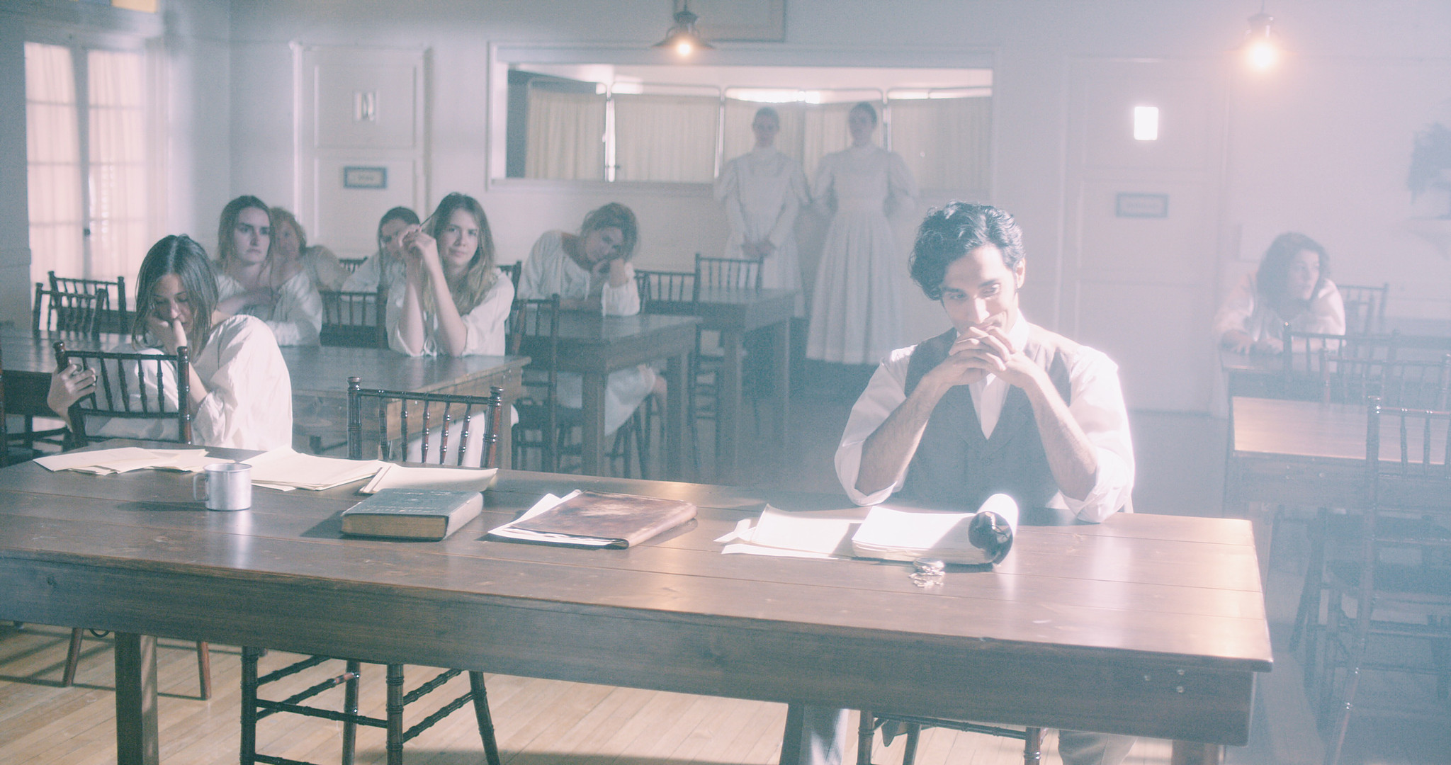 Long communal table in the asylum dining hall, period institutional dressing from The Mad Whale