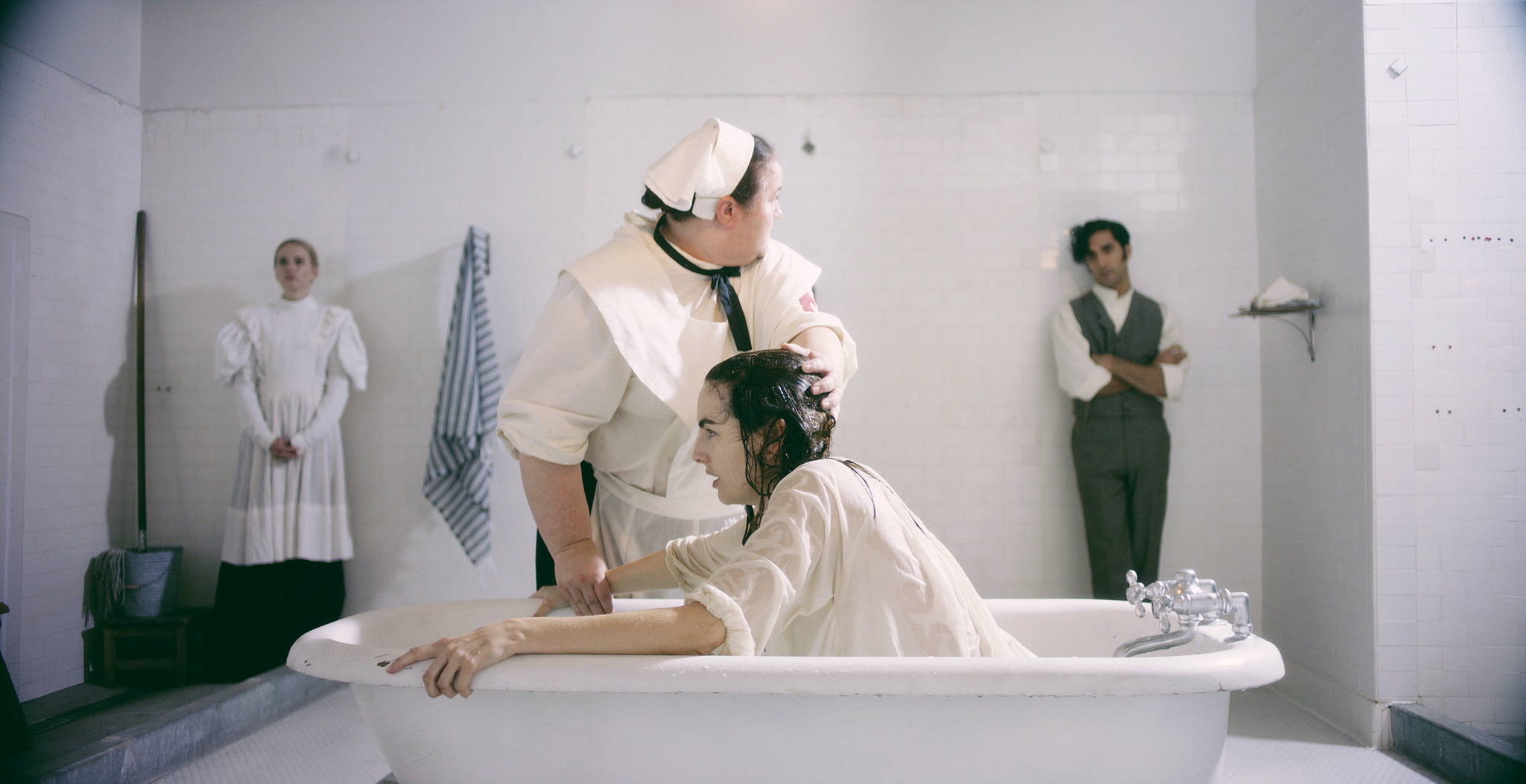 Nurse leaning over a bathtub in the white-tiled asylum bathing room, The Mad Whale