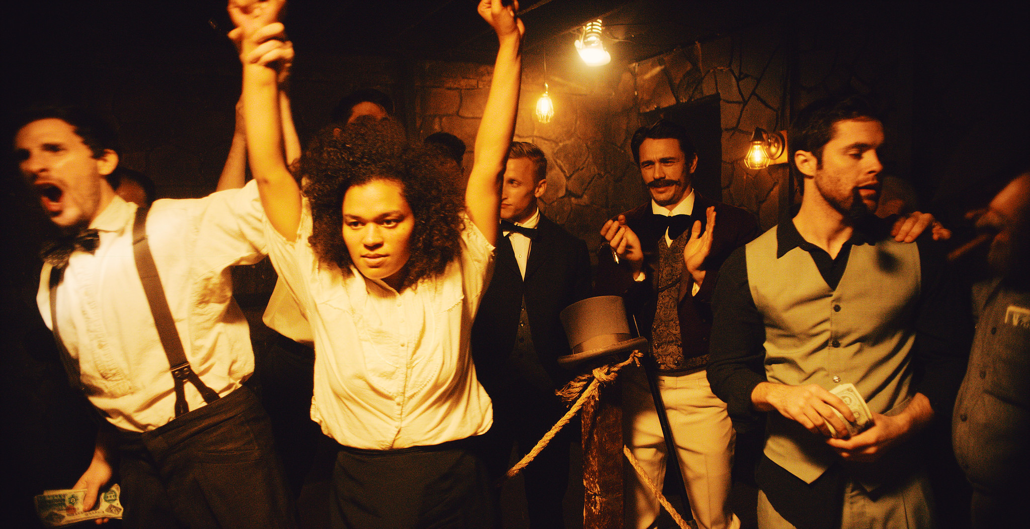 Crowd of period-dressed characters cheering with arms raised in firelight, The Mad Whale