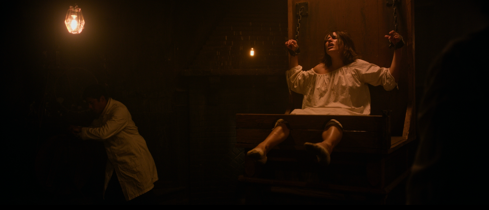 Patient restrained in a chair under a bare bulb in a dark asylum room, The Mad Whale